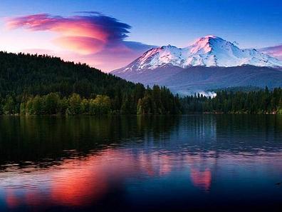 Nature scene of trees and mountains reflection in lake at sunset